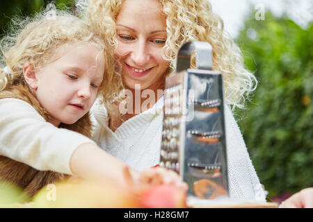 Mutter hilft Tochter Rub Äpfel als Teamarbeit im Herbst im Garten Stockfoto