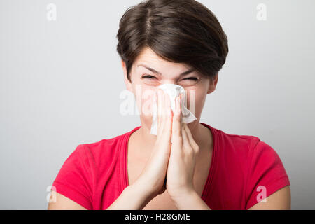 Junge Frau bläst ihre Nase zu hart Stockfoto