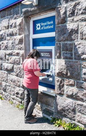 Frau mit RBS Geldautomaten auf der Insel Barra in den äußeren Hebriden. Stockfoto