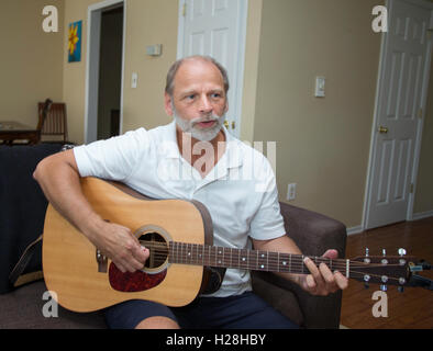 Mann spielt Gitarre in seiner Wohnung Stockfoto