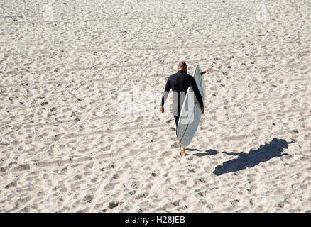 Ein Surfer am Strand mit seinem Brett Stockfoto