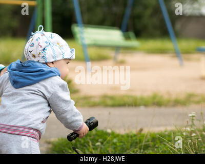 Schönen jungen spielen auf dem Spielplatz mit ihrer Mutter. Der ist gekleidet in ein leichtes Bike Stockfoto