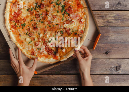 Weibliche Hände unter Stück Pizza Stockfoto