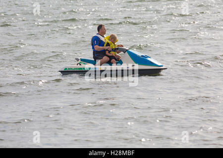 Mann und junge Mädchen auf Jetski in Poole Harbour im September Stockfoto