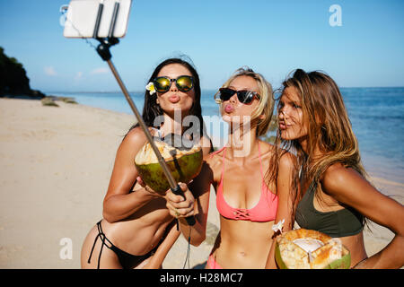 Drei junge Frauen im Badeanzug am Strand Urlaub und Selbstporträt Selfie Stick nehmen. Gruppe von Freundinnen mit Stockfoto