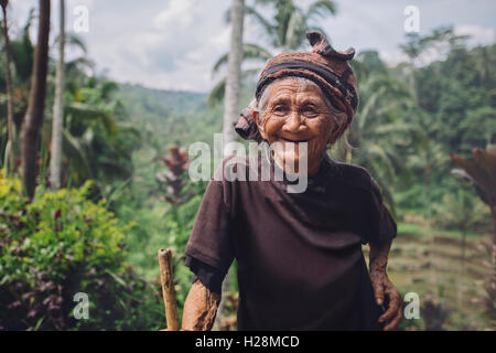 Porträt der glückliche ältere Frau mit einem Stock im Dorf. Lächeln alte weibliche draußen im Lande. Stockfoto