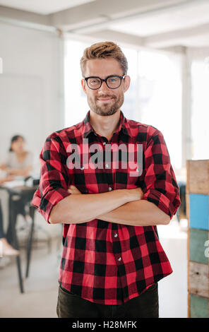 Porträt von glückliches junges Startup Besitzer im Büro mit Kollegen treffen im Hintergrund stehen. Stockfoto