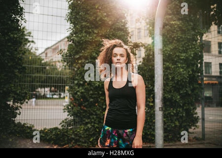 Porträt von schönen jungen Mädchen stehen am Basketballplatz und Kamera ab. Hipster in Casuals. Stockfoto