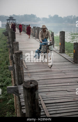 Ein Mann, mit dem Fahrrad entlang der U Bein Brücke bei Sonnenaufgang, Amarapura, Myanmar. Stockfoto