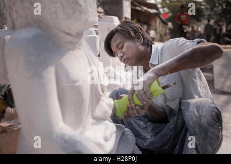 Ein Mann schnitzen einen Marmor Buddha-Statue mit einem Winkelschleifer, Amarapura, in der Nähe von Mandalay, Myanmar. Stockfoto