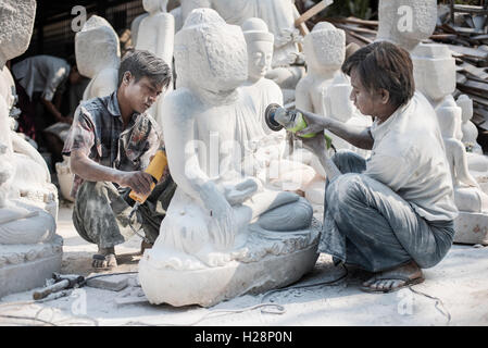 Einheimische Männer schnitzen einen Marmor Buddha-Statue mit einem Winkelschleifer, Amarapura, in der Nähe von Mandalay, Myanmar. Stockfoto