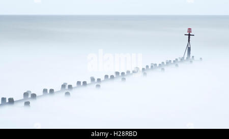 Stürmischer See am West Runton mit Wellen wirbeln um hölzerne Buhnen mit einer langen Belichtungszeit aufgenommen Stockfoto