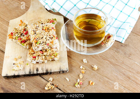 Knusprige Körner Müsliriegel oder Reis Kekse mit einer Glastasse heißen Tee auf Holztisch. Stockfoto