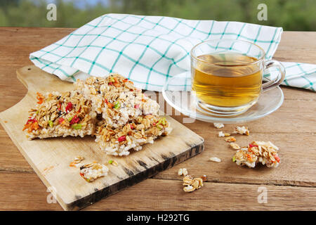 Knusprige Körner Müsliriegel oder Reis Kekse mit einer Glastasse heißen Tee auf Holztisch. Stockfoto