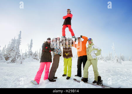 Snowboarder posiert auf blauen Himmel Hintergrund in Bergen Stockfoto