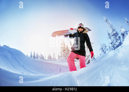 Snowboarder posiert auf blauen Himmel Hintergrund in Bergen Stockfoto