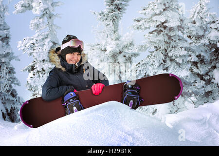 Snowboarder posiert auf blauen Himmel Hintergrund in Bergen Stockfoto