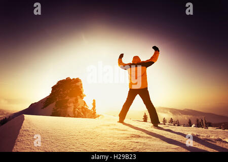 Snowboarder posiert auf blauen Himmel Hintergrund in Bergen Stockfoto