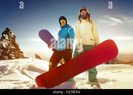 Snowboarder posiert auf blauen Himmel Hintergrund in Bergen Stockfoto