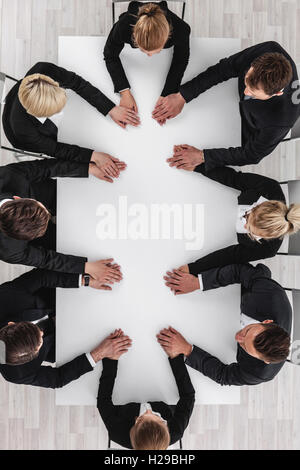 Verschiedene Business-Leute sitzen am Tisch auf einem Treffen und Hand in Hand Stockfoto