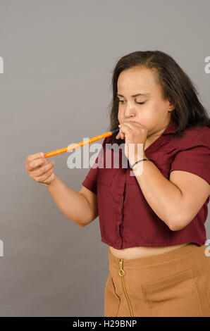 Erwachsene Frau, die versucht, einen langen Ballon in die Luft sprengen Stockfoto