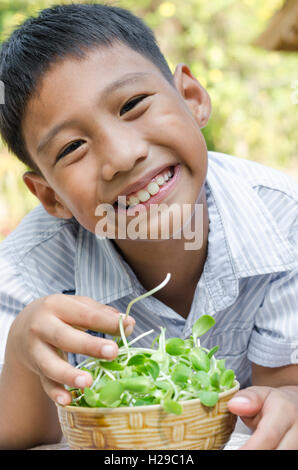 Asiatische Kind genießen, mit Gemüse (Sonnenblumen-Sprossen). Stockfoto