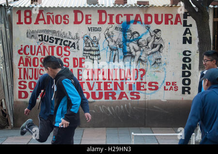 Junge Männer spielen Fußball vor einem politischen Protest-Plakat in La Paz, Bolivien Stockfoto