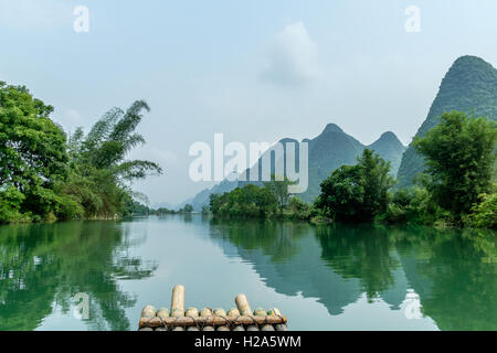 Segeln auf einem Bambusfloß auf dem Yulong Fluss, umgeben von Karstbergen und Bäumen in Guilin, China Stockfoto