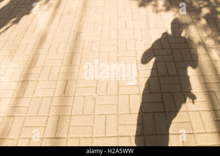 Silhouette der Mann zu Fuß auf Fussgängerzone Pflaster an einem sonnigen Tag Stockfoto