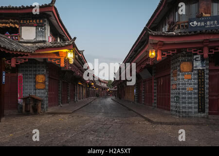 Ruhige Straße mit traditionellen chinesischen Geschäften und Restaurants und hängenden Laternen in der Morgendämmerung in Lijiang, China Stockfoto