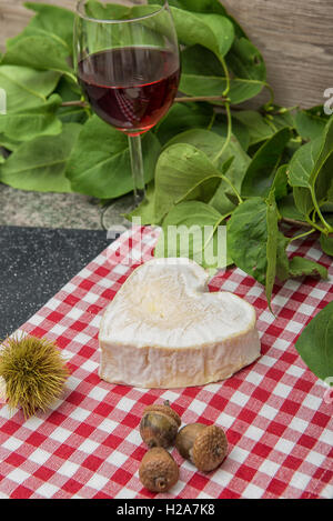 Neufchatel Käse auf eine rot-weiße Tischdecke mit Glasse Wein Stockfoto