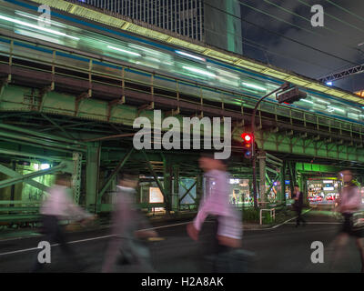 Tokyo nach Einbruch der Dunkelheit. Yamamote Linie auf erhöhten Schienen über Fußgänger in belebten Straßen trainieren. Bewegung verwischt, Gaado-Shita, Yurakucho, Tokyo, Japan Stockfoto