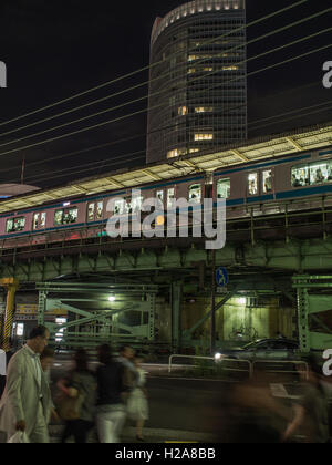 Tokyo nach Einbruch der Dunkelheit. Yamamote Linie auf erhöhten Schienen über Fußgänger in belebten Straßen trainieren. Gaado-Shita, Yurakucho, Tokyo, Japan Stockfoto