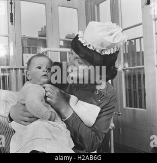 Eine Krankenschwester mit einem Baby in einem Wohngebiet Lehre Krankenhaus in Leicester c1962. Foto von Tony Henshaw Stockfoto