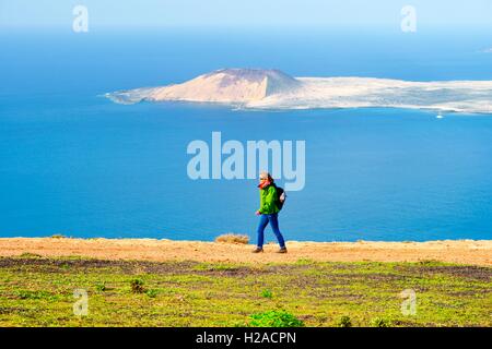 Lanzarote, Kanarische Inseln. Frau wandern Klippen von Risco de Famara bei Guinate 550 m über dem Atlantik. Isla Graciosa im Abstand Stockfoto