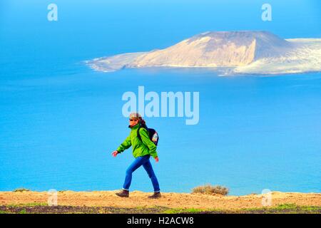 Lanzarote, Kanarische Inseln. Frau wandern Klippen von Risco de Famara bei Guinate 550 m über dem Atlantik. Isla Graciosa im Abstand Stockfoto