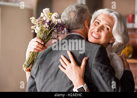 Attraktive Oma lächelnd in die Kamera, während ihr Mann umarmt Stockfoto