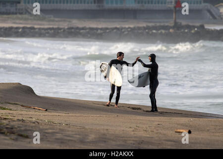 Zwei Surfer gratulieren einander nach ihrer erfolgreichen Fahrten in den Pazifischen Ozean Nord-Kalifornien in der Nähe von Moss Landing. Stockfoto