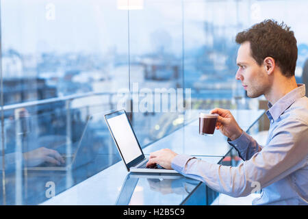 Junger Geschäftsmann, Lesen von e-Mails am Laptop im modernen Café Stockfoto