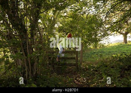 Frau überqueren einen Stil auf einem öffentlichen Wanderweg im Feld in der Nähe von Pentyrch, Cardiff North, South Glamorgan, Wales, UK Stockfoto