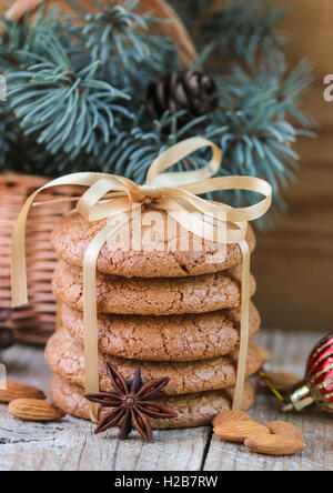 Gewürzte Kekse mit Mandeln. Weihnachtsgeschenke. Runde Kekse mit Band und Fichte Zweig in einem Korb auf dem Tisch gefesselt Stockfoto