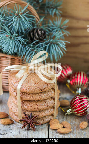 Gewürzte Kekse mit Mandeln. Weihnachtsgeschenke. Runde Kekse mit Band und Fichte Zweig in einem Korb auf dem Tisch gefesselt Stockfoto