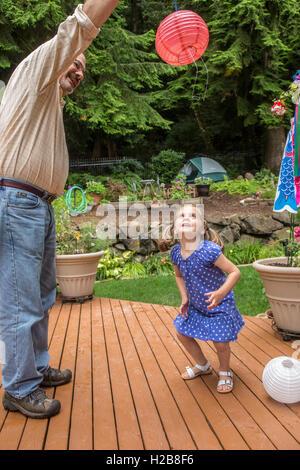 Drei Jahre altes Mädchen spielen mit einer Papierlaterne mit ihrem Großvater in Issaquah, Washington, USA Stockfoto