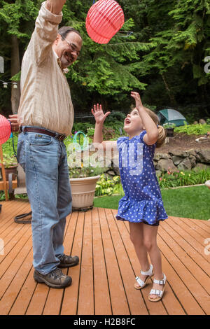 Drei Jahre altes Mädchen spielen mit einer Papierlaterne mit ihrem Großvater in Issaquah, Washington, USA Stockfoto