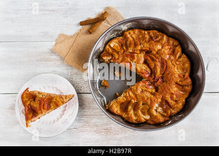 Zimt Kuchen mit Apfelscheiben und Zucker obenauf. Kuchen backen dish, Stück Kuchen auf Vintage weißen Teller. Hölzerne Rückseite Stockfoto