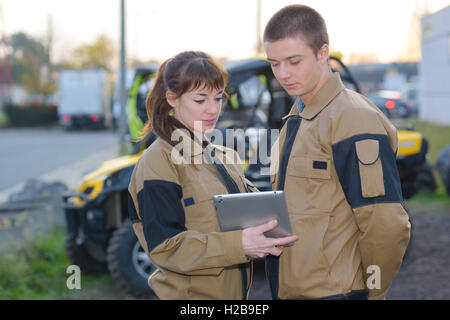 Mechanik auf der Suche auf Tablet-Computer vor geparkten quads Stockfoto