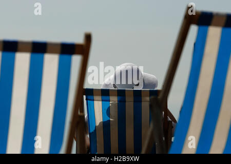 Eine Frau sonnt sich in der hohen Temperaturen und Sonnenschein in Brighton in East Sussex Stockfoto