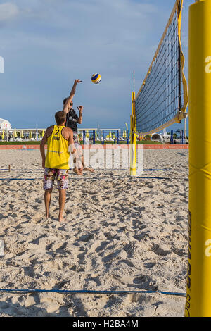 Junger Mann in Bewegung spielt im Beach-Volleyball. Stockfoto