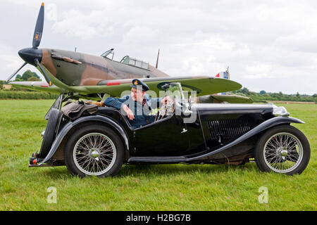 Re-Enactor gekleidet als Battle of Britain Pilot stellte in einem Zeitraum-authentische MG-Sportwagen und eine Hawker Hurricane Kampfflugzeug Stockfoto