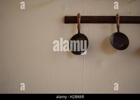 Zwei schwarze Eisenpfannen hängen weiße Wand Stockfoto